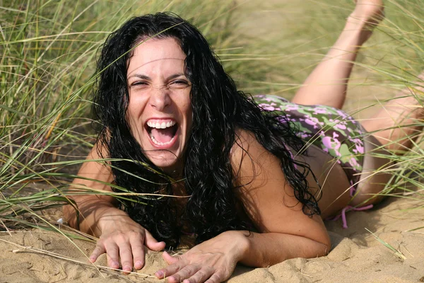 Fille en bikini riant à la plage dans la grande herbe et le sable — Photo