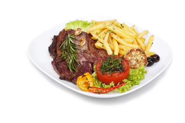 Filete a la parrilla con papas fritas y verduras en el plato — Foto de Stock