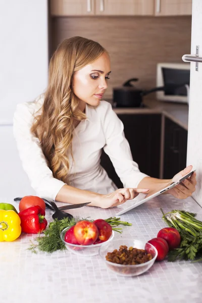 Unga flickan i köket letar du efter ett recept på tablett — Stockfoto