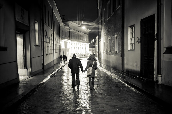 A girl and a boy walking in the old town street at night, haldin
