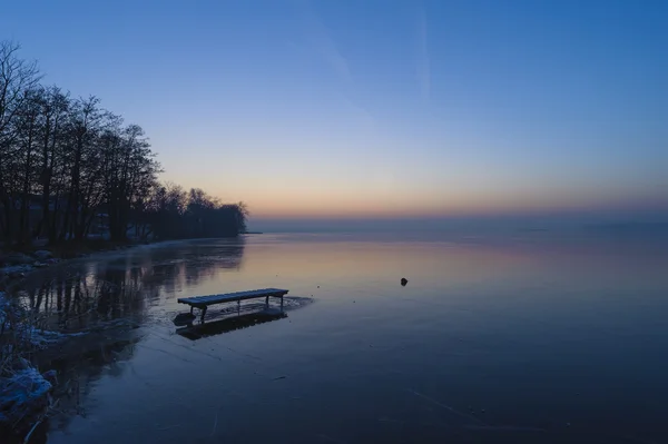 Frusen sjö med en lake väg överbrygga i solnedgången. — Stockfoto