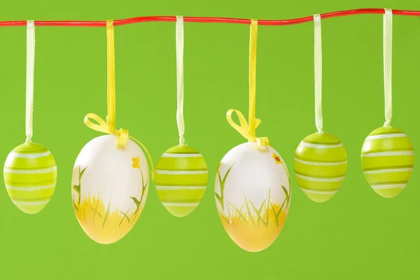 Ostereier hängen an roter Schnur auf grünem Grund. — Stockfoto