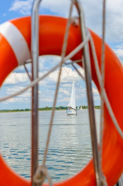 Segelbåt i sjön, Foto taget genom orange livbälteplachetnice v jezeře, fotografie pořízené prostřednictvím oranžové záchranný pás. — Stockfoto