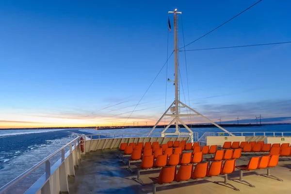 Orange outdoor deck chairs on ferry sailing in frozen sea. — Stock Photo, Image