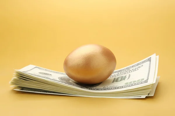 A golden egg on dollars — Stock Photo, Image