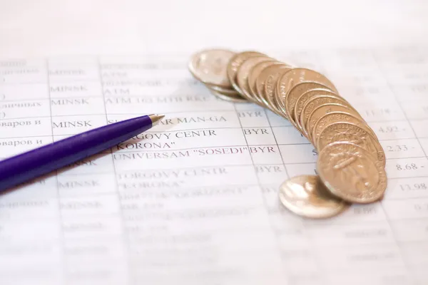Ручка и монеты на деловой бумаге — стоковое фото