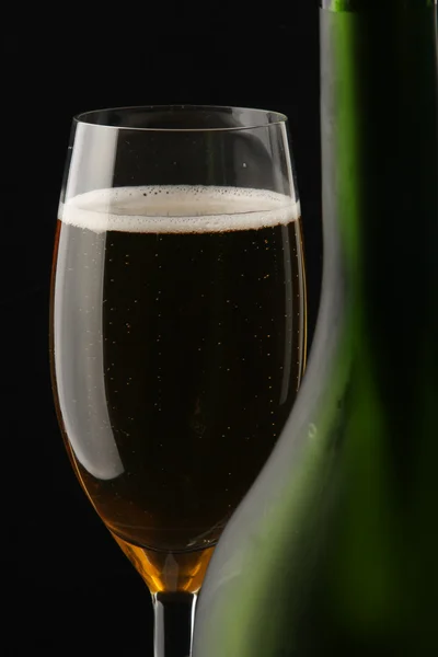 Sklenka šampaňského poblíž láhev — Stock fotografie