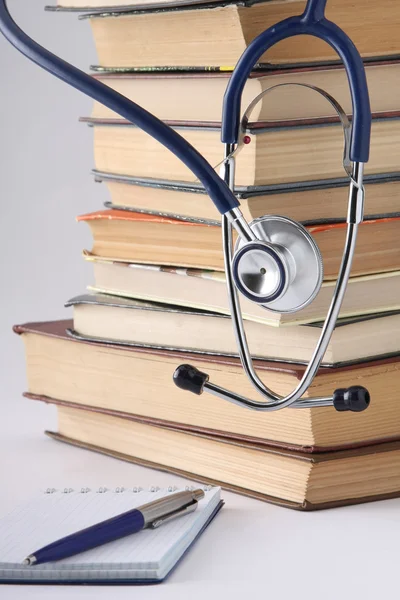 Stethoscope on a pile of books and a notebook with a pen — Stock Photo, Image