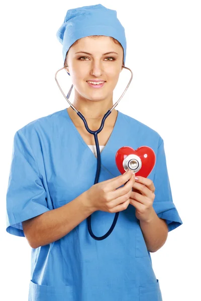 Doctor with stethoscope examining red heart — Stock Photo, Image