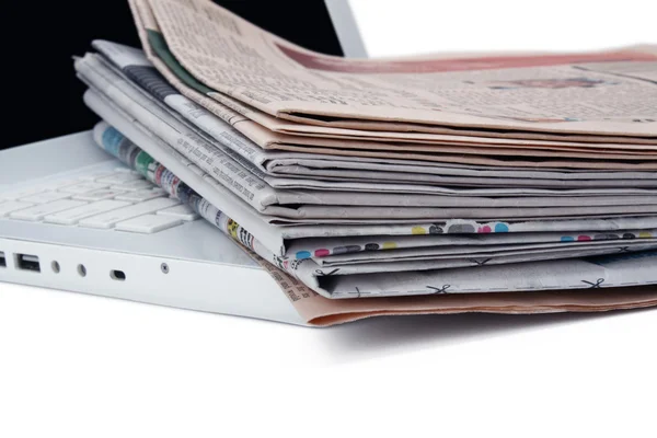 Stack of newspaper next to a laptop — Stock Photo, Image