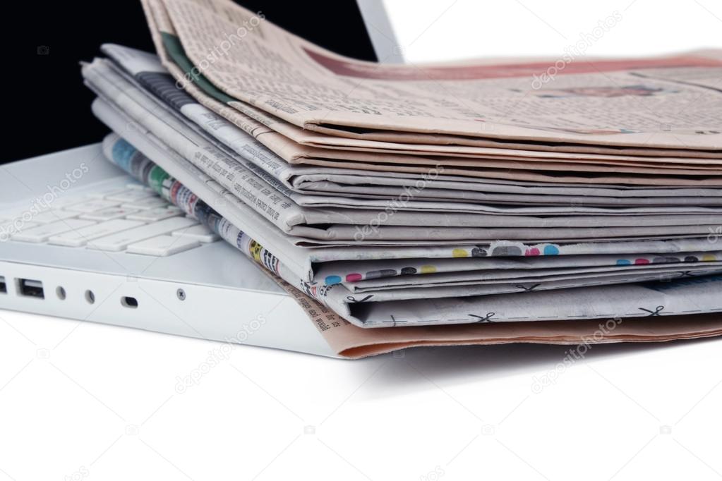 Stack of newspaper next to a laptop