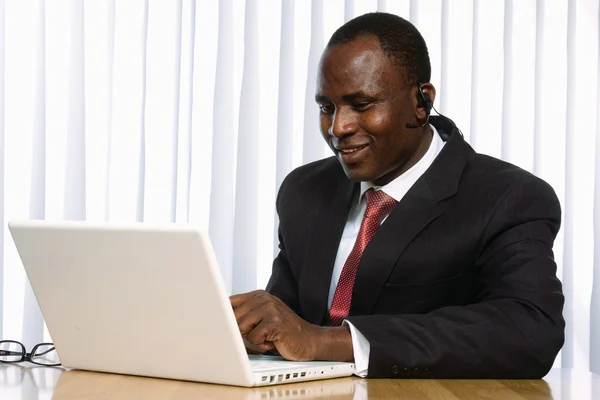 Афроамериканец сидит на столе с ноутбуком — стоковое фото