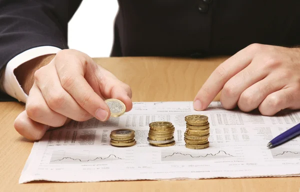 Businessman putting the coins in columns Royalty Free Stock Images