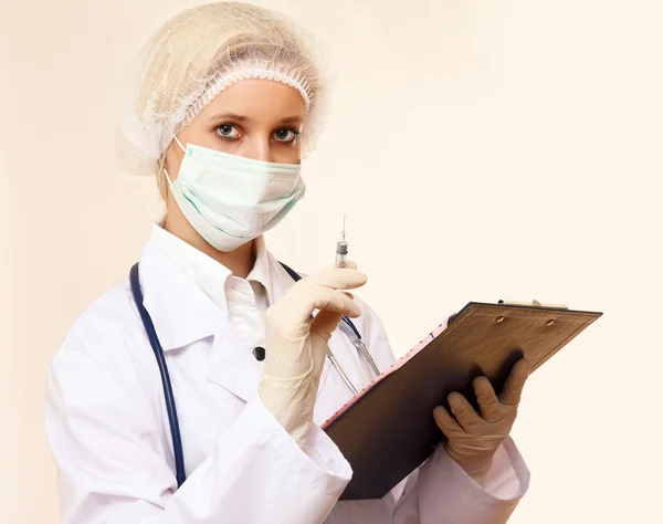 Nurse in mask with syringe and holding clipboard — Stock Photo, Image