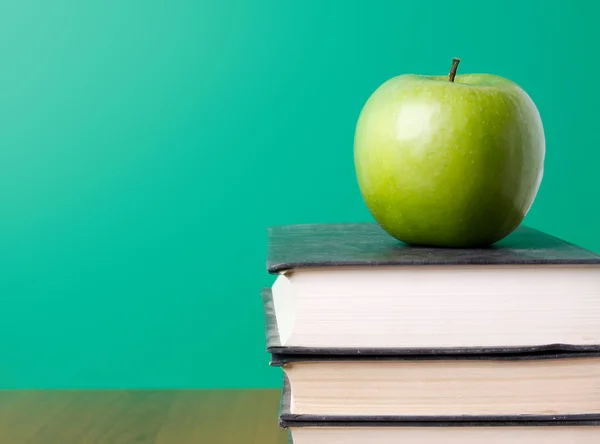Зеленое яблоко на куче книг — стоковое фото