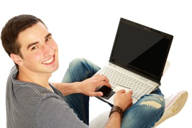 Yerde dizüstü bilgisayarı olan bir adam oturuyor.