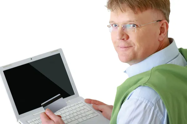 男子坐在一台笔记本电脑，手持一张信用卡 — 图库照片