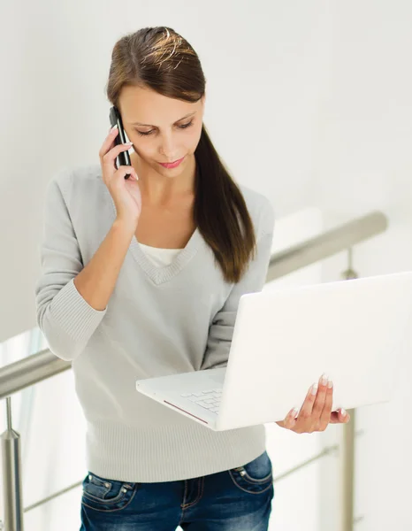 Woman work on laptop and talking on the phone — Stock Photo, Image