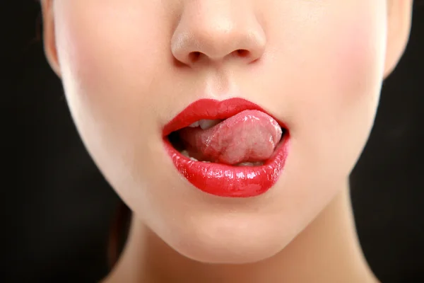 Mujer con lápiz labial rojo y lamiéndose el labio — Foto de Stock