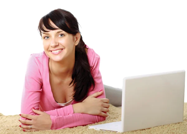 Young girl with a laptop lying on the floor Stock Picture