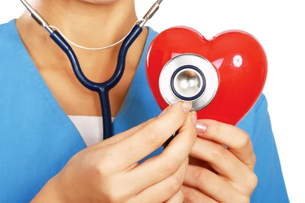 Doctor with stethoscope examining red heart — Stock Photo, Image
