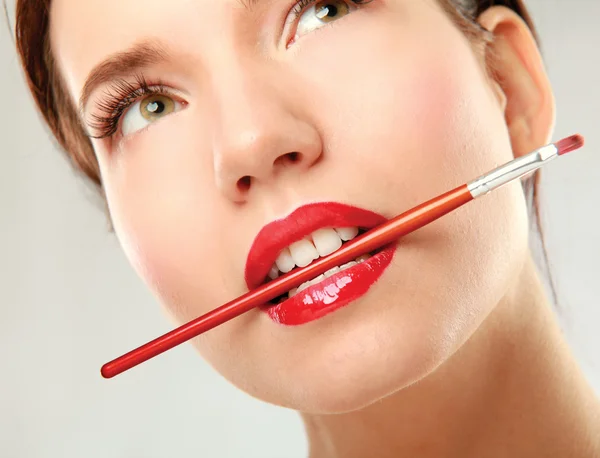 Los labios de la mujer sosteniendo maquillaje cepillo — Foto de Stock