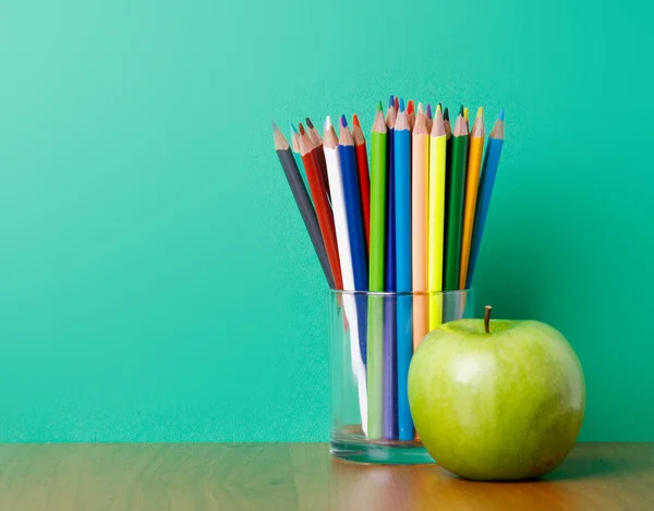 Gläser mit Bleistiften und grünem Apfel — Stockfoto