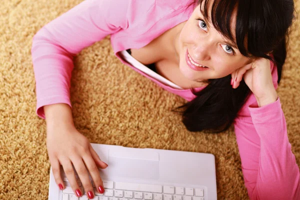 Girl with a laptop lying on the floor — Stock Photo, Image