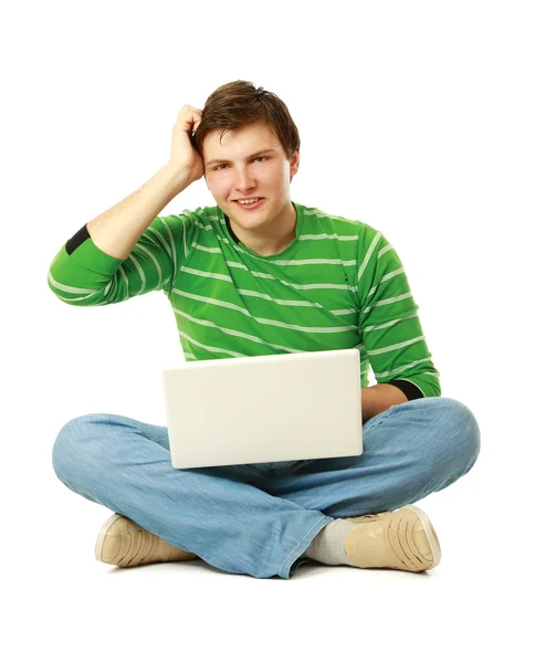 Genç adam oturmuş ve bir dizüstü bilgisayar kullanarak — Stok fotoğraf