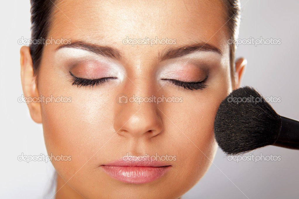 Young adult woman applying blusher