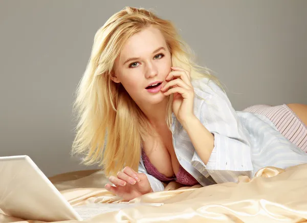 Woman lying on the bed with laptop — Stock Photo, Image