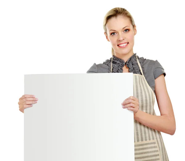 Kvinna iklädd förkläde och poserar bakom en vit blank — Stockfoto