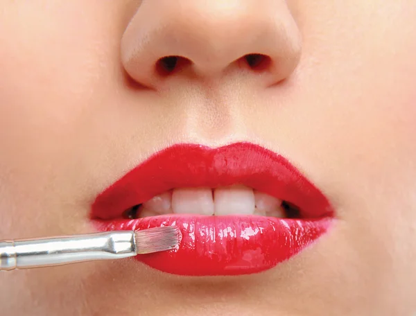 Los labios de la mujer sosteniendo maquillaje cepillo — Foto de Stock