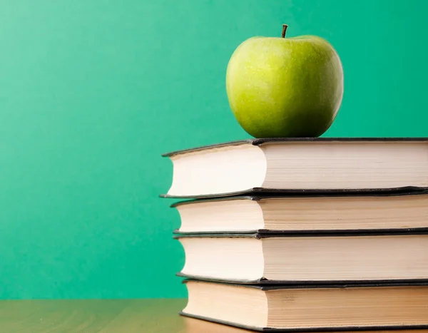 Green apple on a pile of books — Stock Photo, Image