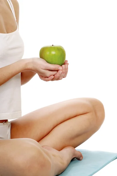 Mujer joven haciendo yoga y sosteniendo manzana —  Fotos de Stock