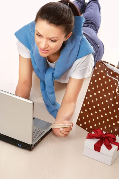 Femme couchée avec un ordinateur portable, carte de crédit et boîte cadeau — Photo
