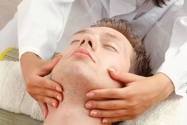 Man får ansiktsmassage från en kvinna — Stockfoto