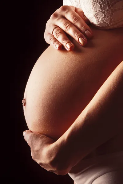 Беременная женщина прикасается руками к животу — стоковое фото