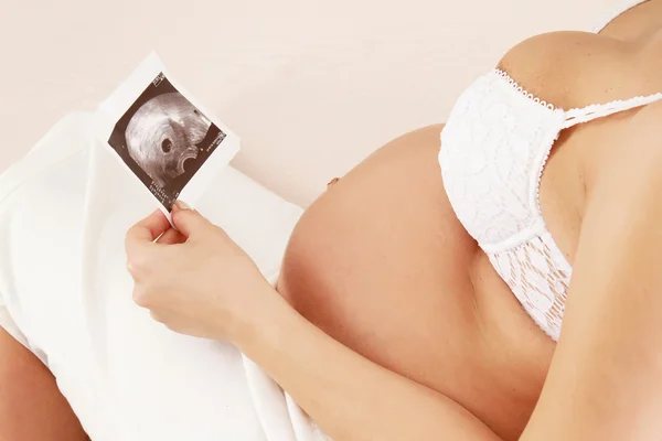 Pregnant woman holding an ultrasound picture of her baby — Stock Photo, Image