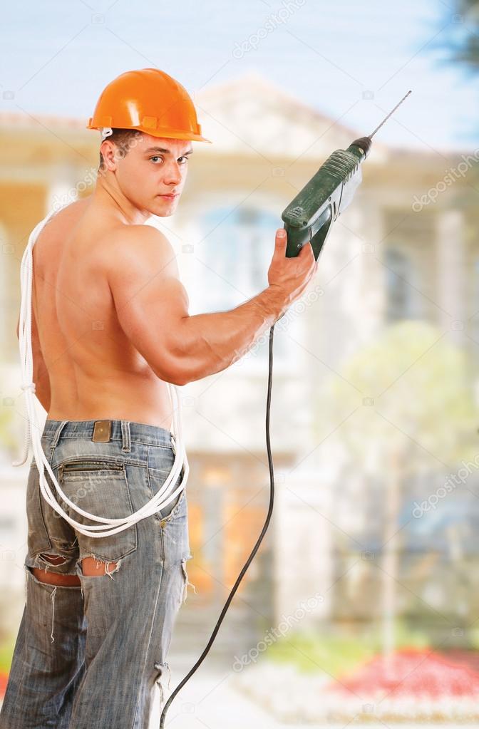 Muscular worker with a drill outdoors