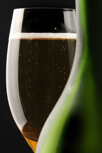A glass of champagne behind a bottle — Stock Photo, Image
