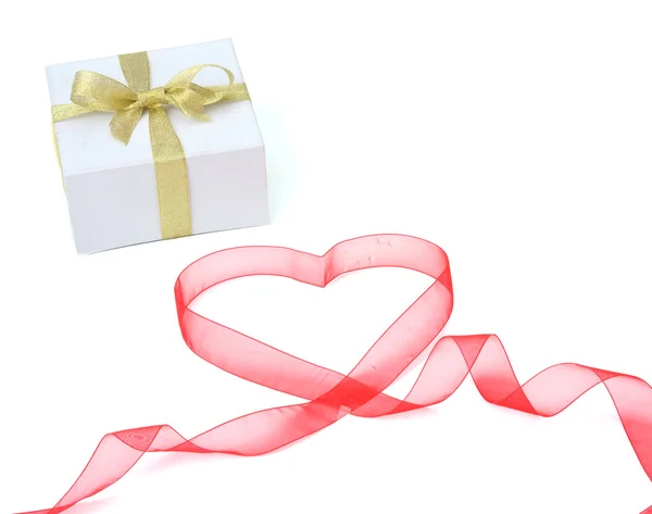 Gift and a red ribbon shaping heart — Stock Photo, Image