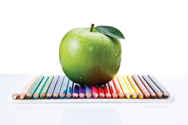 Colored pencils and a green apple