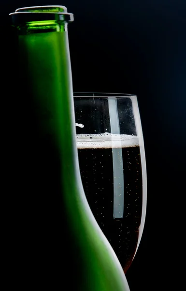 Glass of champagne behind a bottle — Stock Photo, Image