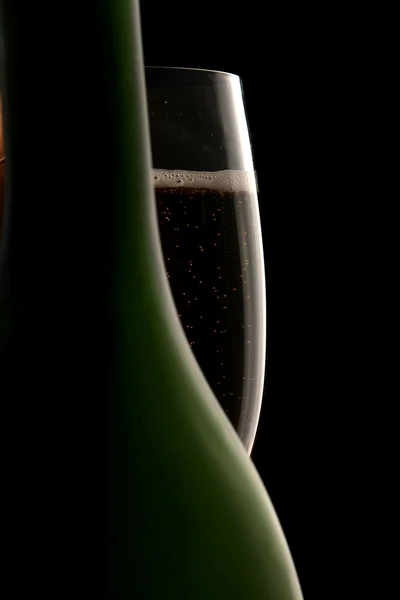 Glas champagne bakom en flaska — Stockfoto