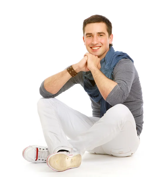 Молодой улыбающийся парень сидит на полу — стоковое фото