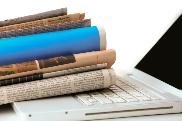 Stapel krant naast een laptop. — Stockfoto