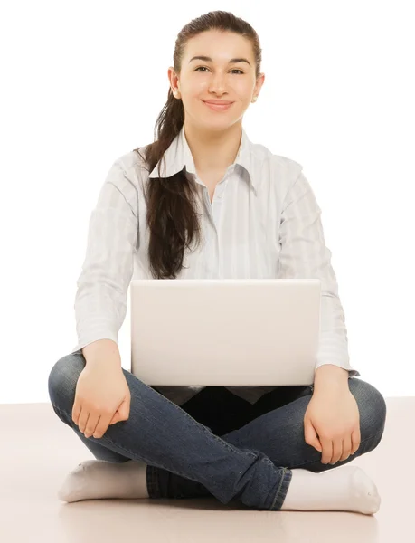 En ung flicka sitter på golvet med en bärbar dator — Stockfoto