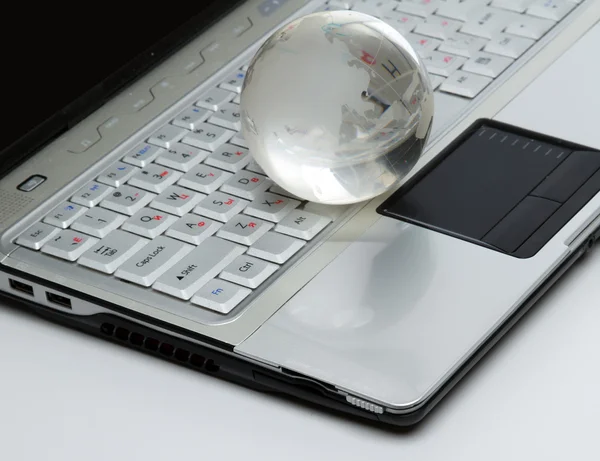 Crystal-glass globe on keyboard of modern notebook. — Stock Photo, Image