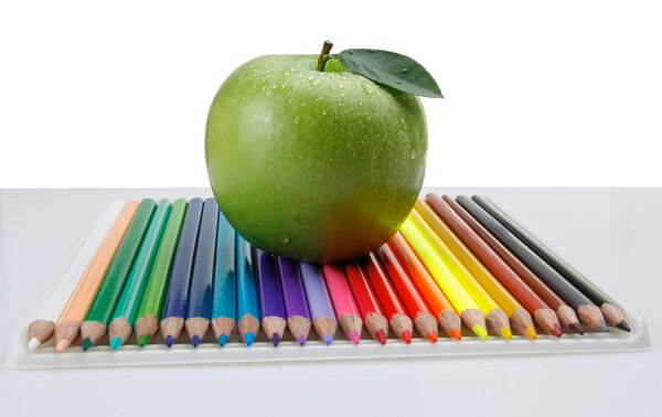 Colored pencils and a green apple.